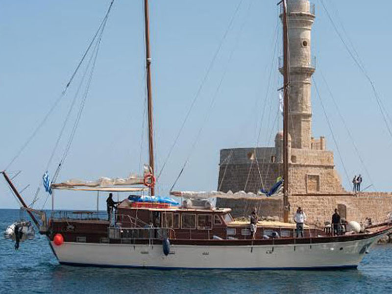 Greek Sea Cruises’s Gulet 68 boat rental passing a lighthouse while cruising around the Greek Islands